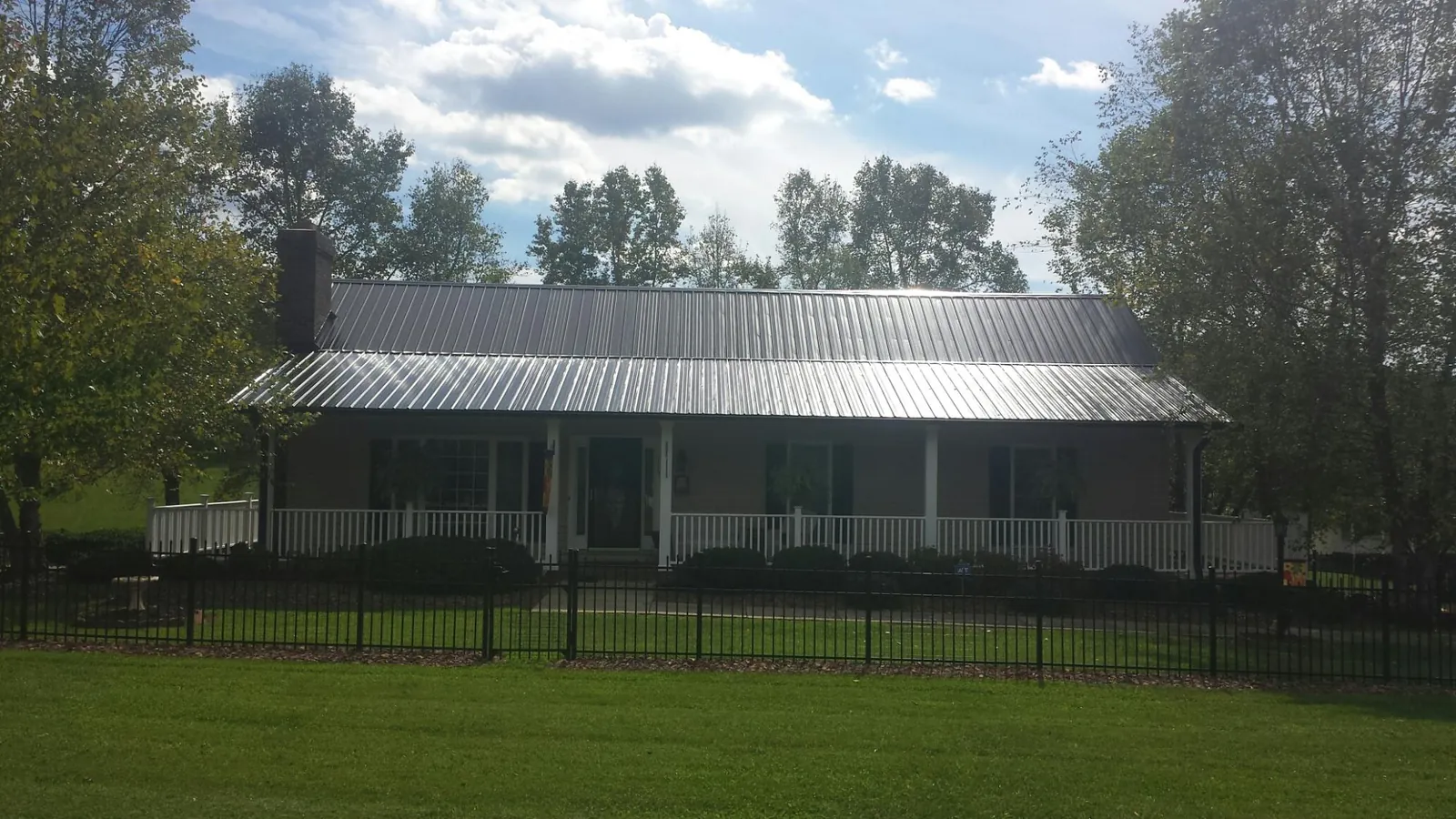 Gray metal roof on a brick ranch with a full width front porch — Gutter Guard Installation work by our crew in Woodbine